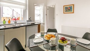 A modern kitchen with a sink, countertop, and a dining area with a table set for breakfast. - 3 bedroom accommodation in Skipton (Skipton)
