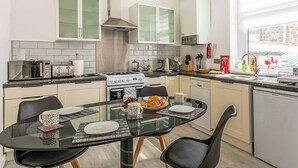 A modern kitchen with a dining table, chairs, and various appliances. - 3 bedroom accommodation in Skipton (Skipton)
