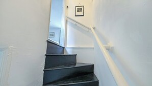 A staircase with a handrail, a door at the top, and a framed picture on the wall. - 2 bedroom accommodation in Cheltenham (Cheltenham)