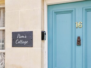 A building with a sign reading 'Pam's Cottage' and a blue door with the number 16. - 2 bedroom accommodation in Cheltenham (Cheltenham)
