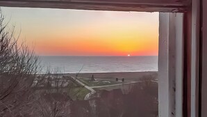 Une vue sur l’océan au coucher du soleil, avec un banc et une clôture au premier plan.