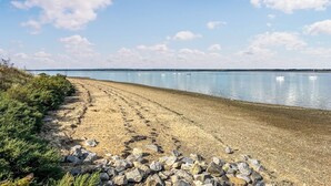 Ein Strand mit felsigem Ufer und ruhigem Wasser.
