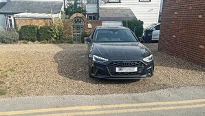 Ein schwarzes Auto steht auf einem graven befestigten Weg.