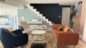Ein modernes Wohnzimmer mit Treppe, Sofa, Couchtisch und Schreibtisch.