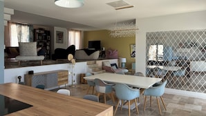 Ein moderner Wohnraum mit Essbereich, einer Sofagarnitur, einem Fernseher und einer Treppe zu einer oberen Ebene.