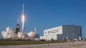 El lanzamiento de un cohete SpaceX, con un gran edificio industrial en el fondo, identificado con la leyenda 'SPACEX'.
