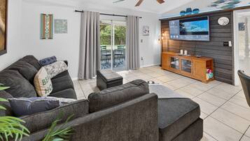 A modern living room with a sectional sofa, a flat-screen TV, and a wooden entertainment unit.