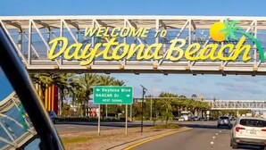 Un cartel de carretera con la leyenda 'Welcome to Daytona Beach' e indicaciones hacia Daytona Blvd y NASCAR Dr.