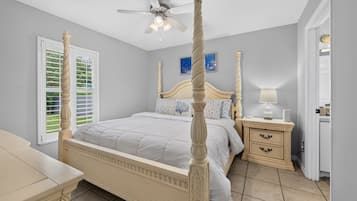 A four-poster bed with a ceiling fan, a bedside table with a lamp, and a nightstand with a lamp.