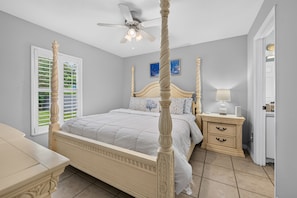 A four-poster bed with a ceiling fan, a bedside table with a lamp, and a nightstand with a lamp.