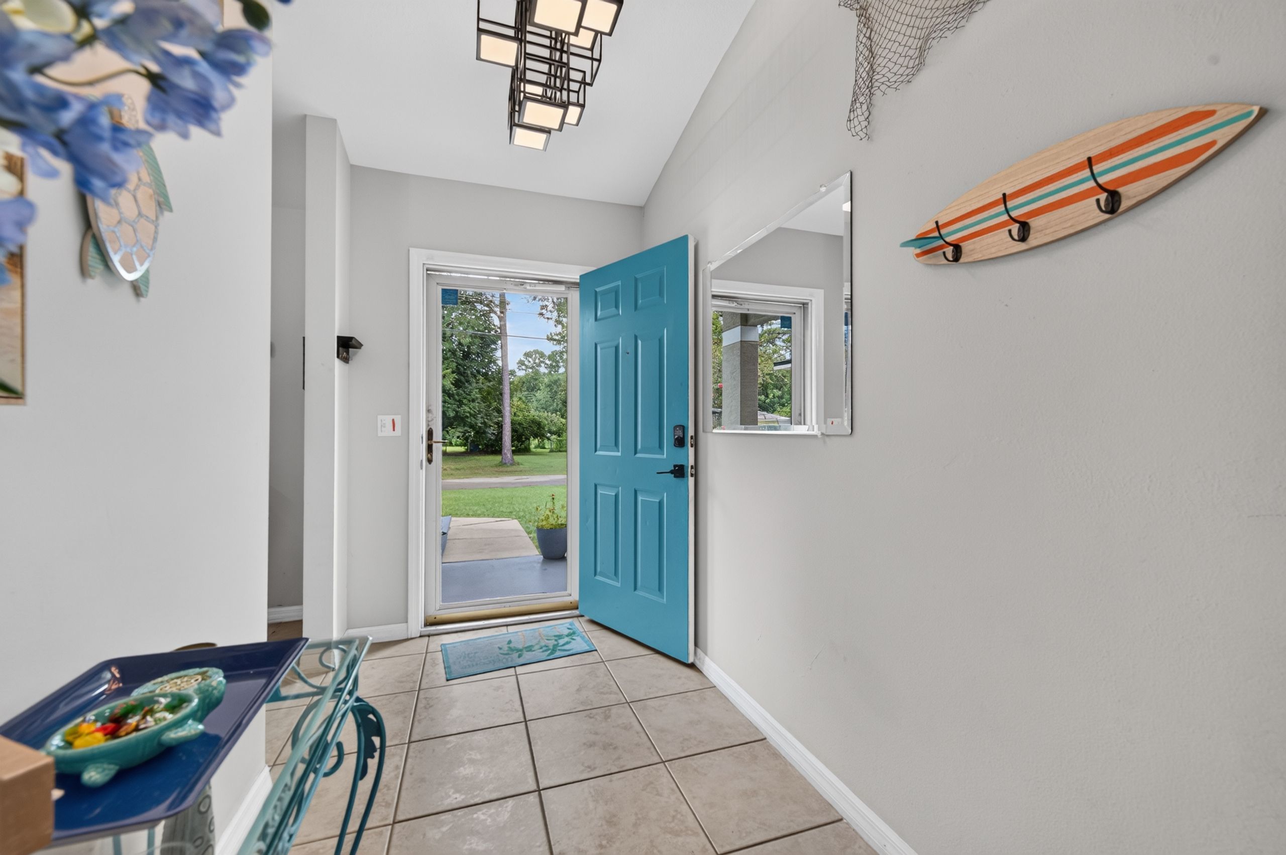 A hallway with a blue door, a surfboard decoration, and a small window.