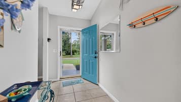 A hallway with a blue door, a surfboard decoration, and a small window.