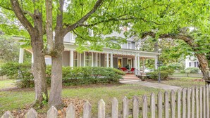 A house with a porch, a wooden fence, and a tree in the foreground. - Walk to Waterfront: Downtown Elizabeth City Home! (Elizabeth City)