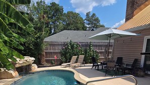 A backyard with a swimming pool, patio furniture, and a wooden fence. - GameDay! University of South Alabama Poolside Getaway🇺🇲Veteran Own ⚓️ (Mobile)