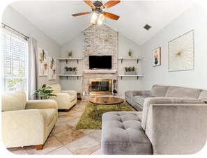Un salon avec une cheminée, des canapés et un ventilateur de plafond.