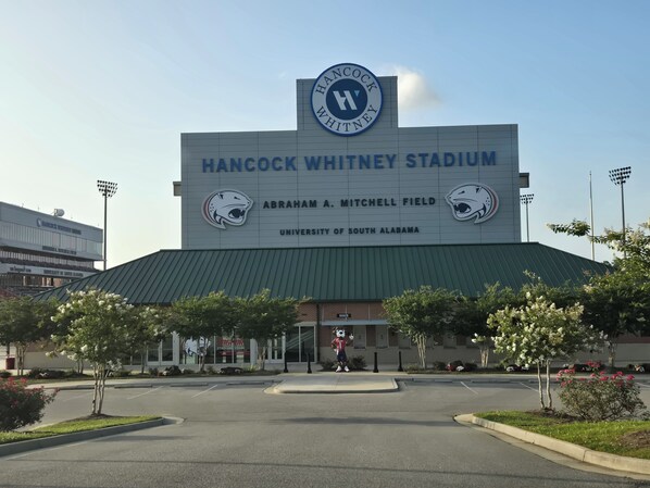 Estadio Hancock Whitney con un letrero grande, una figura de mascota y un estacionamiento.
