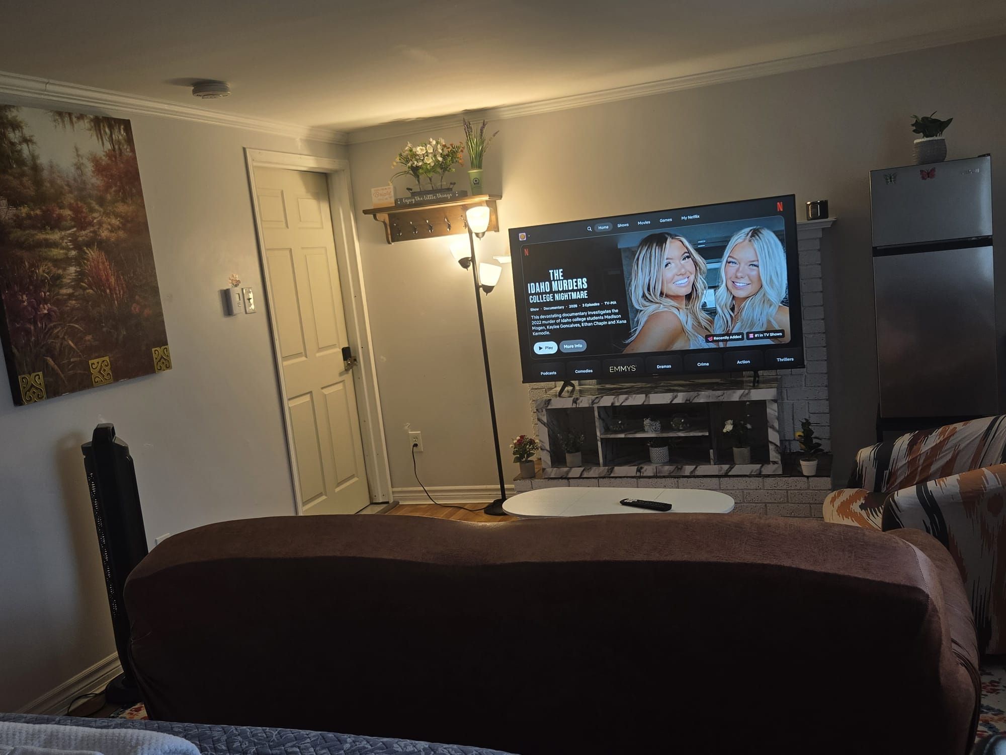 A living room with a flat-screen TV mounted on the wall, a fireplace, and a door.
