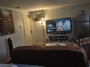 Ein Wohnzimmer mit Flachbildfernseher an der Wand, einem Kamin und einer Tür.