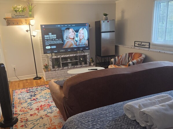 Un dormitorio con televisión, chimenea, cama y ventana.