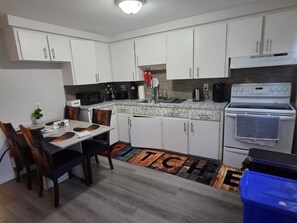 Cocina compacta con armarios blancos, microondas, cafetera y estufa.