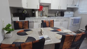 Una cocina moderna con armarios blancos, encimera de mármol y mesa de comedor con un diseño geométrico original.