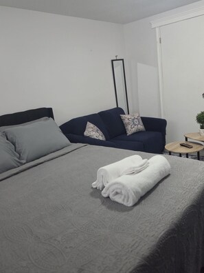Una habitación de hotel con una cama, un sofá, una mesita y un espejo.