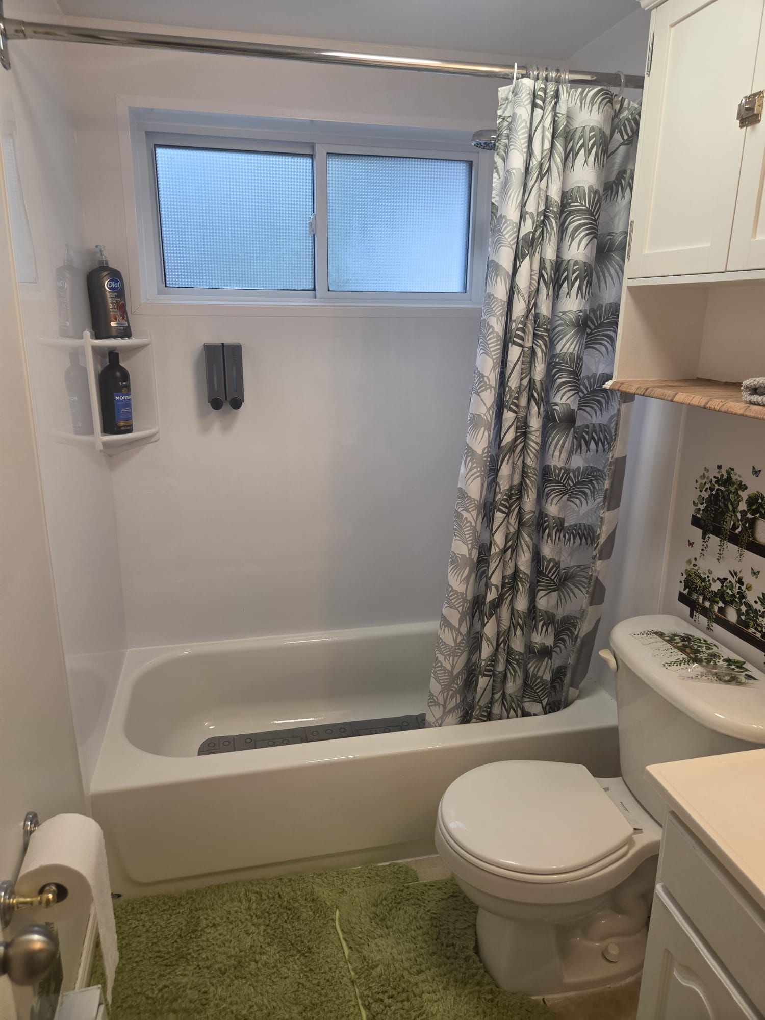 A bathroom with a bathtub, toilet, and a window above the bathtub.