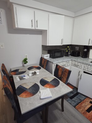 A modern kitchen with white cabinets, a microwave, a toaster, and a coffee maker.
