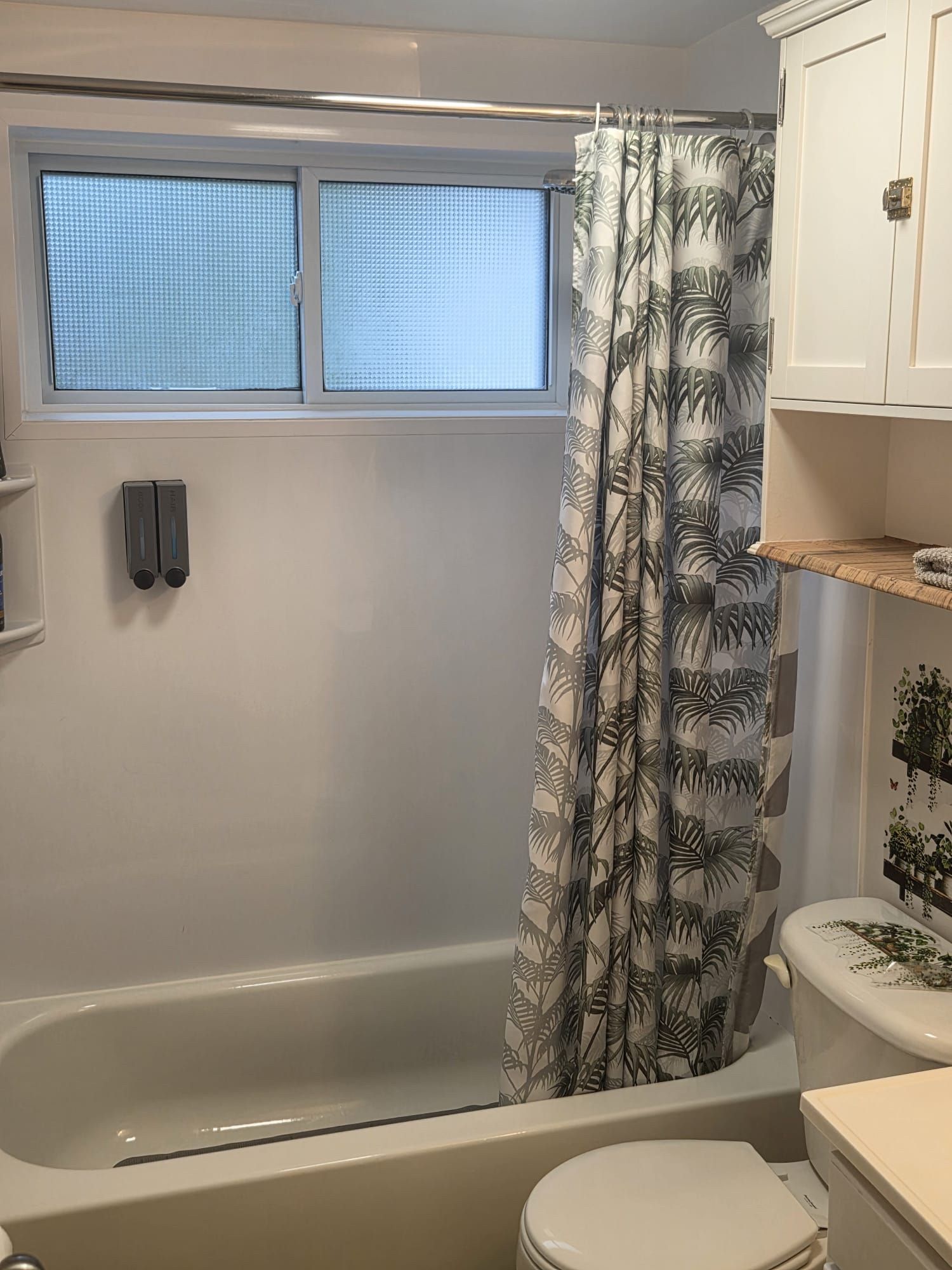 Une salle de bain avec une baignoire, des toilettes et une fenêtre équipée de stores.