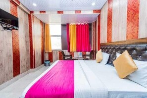 Ein Hotelzimmer mit einem großen Bett, einem an der Wand befestigten Fernseher und einem Fenster mit Vorhängen.