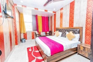 Ein Schlafzimmer mit einem großen Bett, einem Holzkopfteil, einer Wand mit roten und weißen Mustern, einem Deckenventilator und einem Fenster mit Vorhängen.