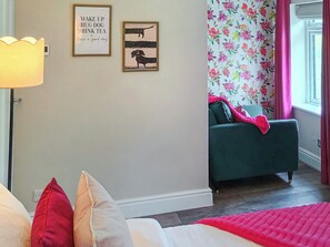 A bedroom with a bed, a green sofa, a wall with floral wallpaper, and two framed pictures. - 2 bedroom accommodation in Stanhope, near Bishop Auckland (Stanhope, near Bishop Auckland)