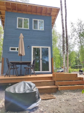 A two-story house with a deck, a table with chairs, and a covered outdoor area. - Birch Cabin @ Creekside Campground (Willow)