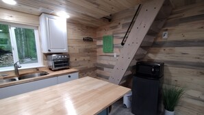 A kitchen with wooden walls, a sink, a stove, and a microwave. - Birch Cabin @ Creekside Campground (Willow)