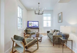 A living room with a television, two sofas, a coffee table, and a chandelier.