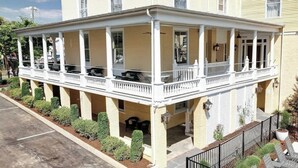 Un edificio de dos pisos con un porche cubierto y un pequeño jardín.