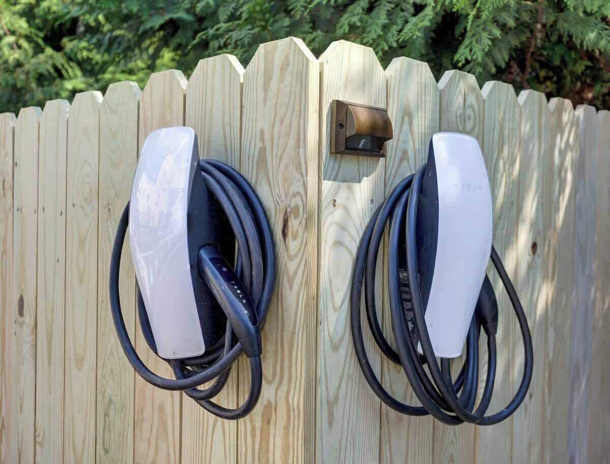 Uma cerca de madeira com duas estações de carregamento para veículos elétricos.