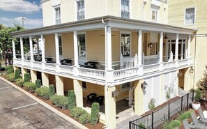 A two-story building with a covered porch and a small garden area.
