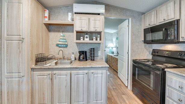 A kitchen with light wood cabinets, a black stove, a microwave, and a coffee maker. - 2 Mi to Anna Maria Island: Newly Built Home! (Bradenton)