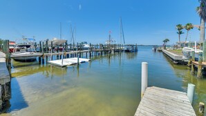 A marina with boats docked at wooden piers, clear water, and palm trees along the shore. - 2 Mi to Anna Maria Island: Newly Built Home! (Bradenton)