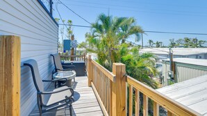 A wooden deck with two chairs and a table, overlooking a residential area with palm trees and houses. - 2 Mi to Anna Maria Island: Newly Built Home! (Bradenton)