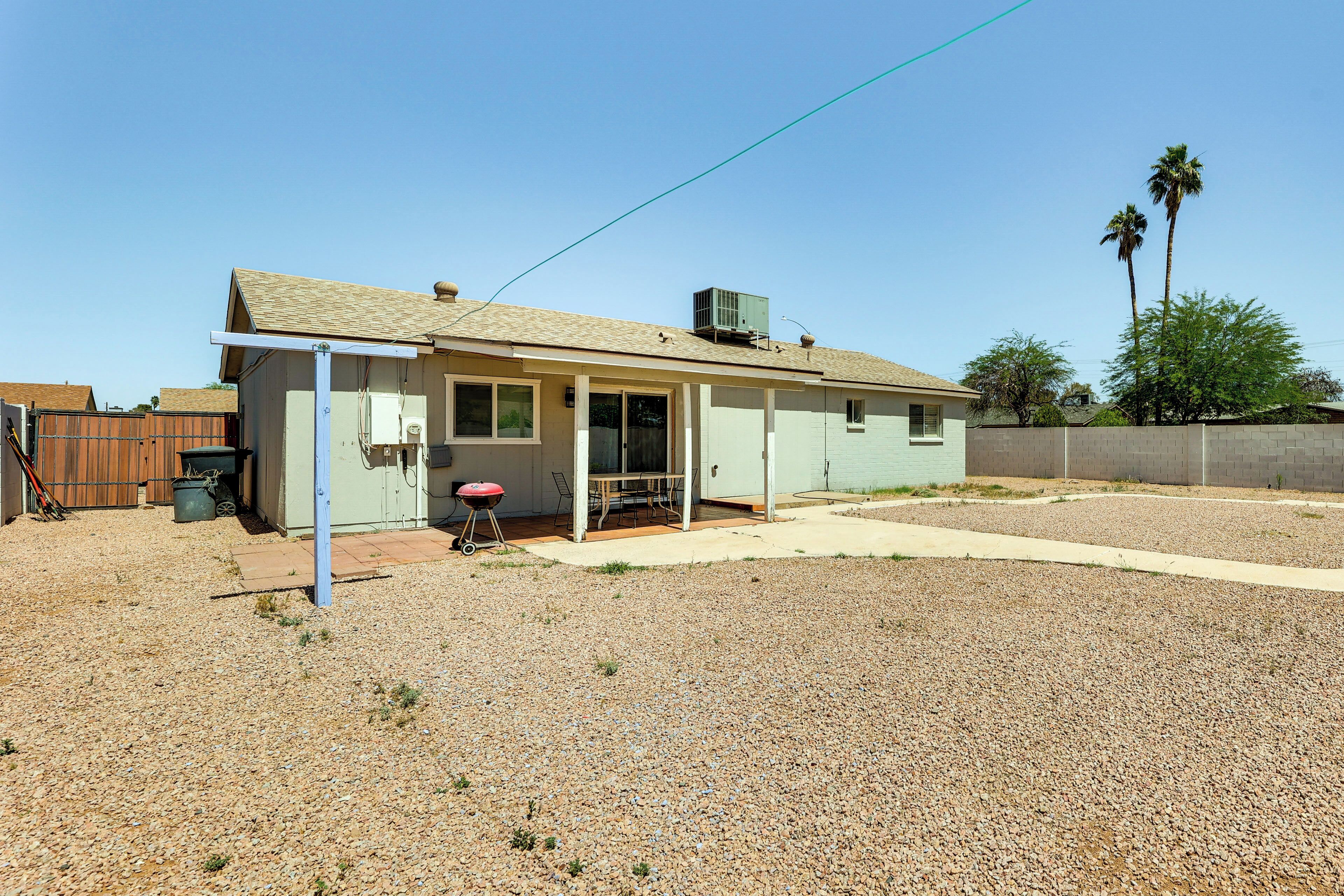 A single-story house with a covered patio, a fenced yard, and a clear sky.