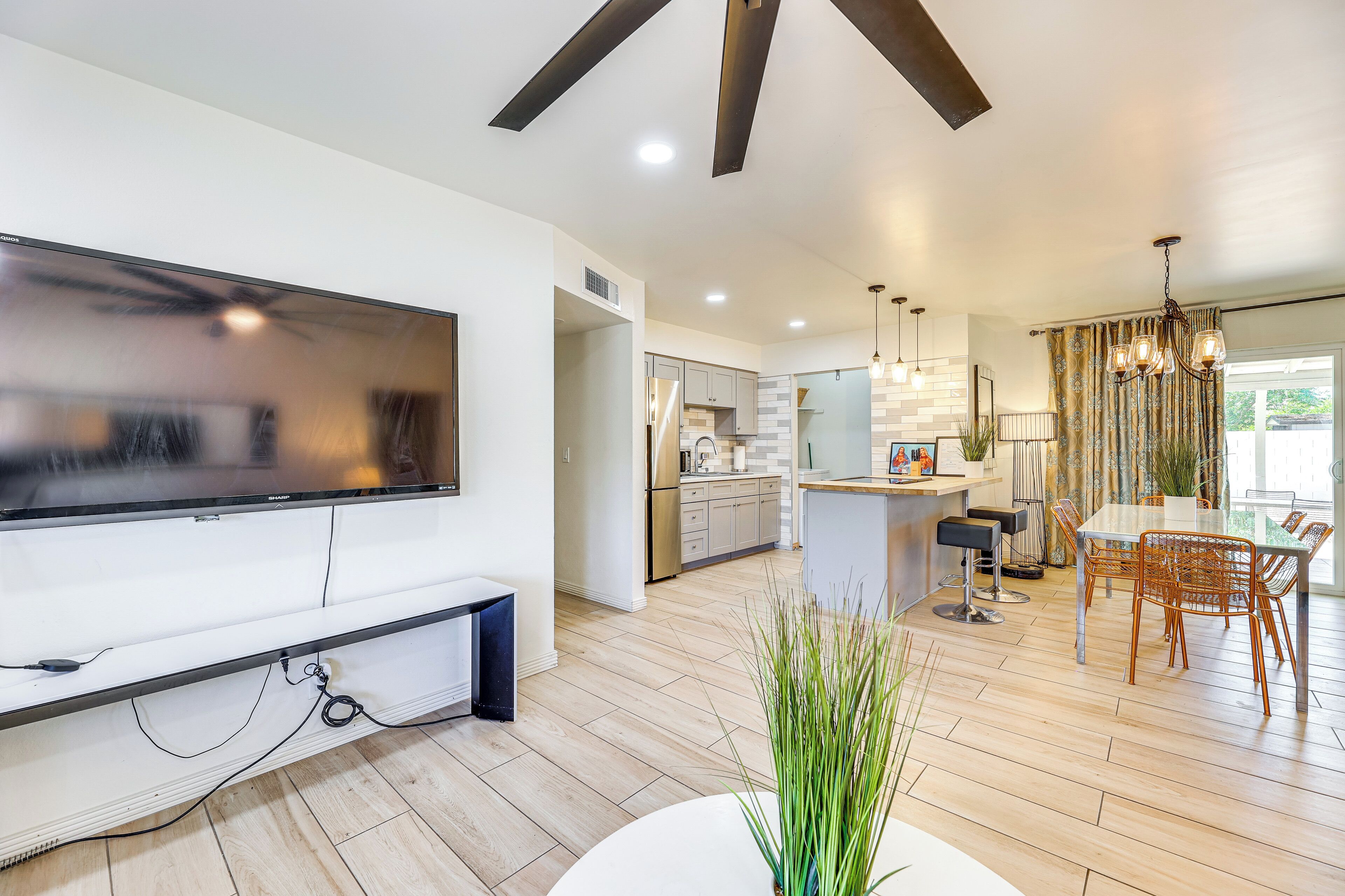 A modern kitchen with a large TV, wooden flooring, and a dining area with a table and chairs.
