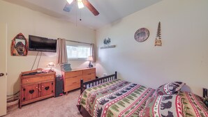 A bedroom with a bed, a dresser, a television, a ceiling fan, and wall decorations. - Family Fun on Ruby Creek: Cusick Hideaway w/ Dock (Cusick)