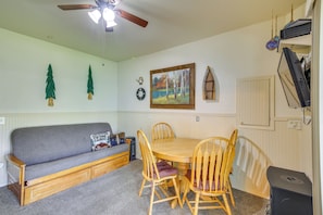 A cozy room with a sofa, wooden dining table, and chairs, a ceiling fan, and a painting on the wall. - Family Fun on Ruby Creek: Cusick Hideaway w/ Dock (Cusick)