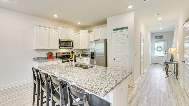 Keittiössä on valkoiset kaapit, graniittitaso ja ruostumattomasta teräksestä valmistetut kodinkoneet.