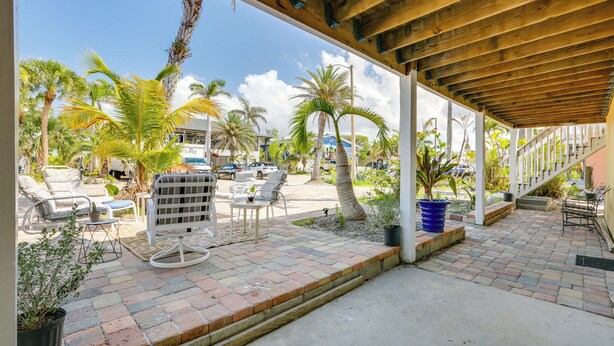An outdoor patio area with seating, palm trees, and a covered walkway. - Walk to Beach: Fort Meyers Home w/ Patio! (Fort Myers Beach)