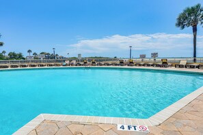 Relax by the inviting pool surrounded by lounge chairs and palm trees.