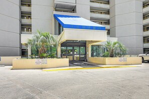 Welcome to the entrance of this building, featuring a glass door and planter boxes with lush greenery.