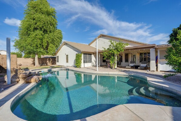 A swimming pool with a curved edge, surrounded by a patio area with outdoor furniture. - Private Pool: Group-Friendly Gilbert Getaway! (Gilbert)